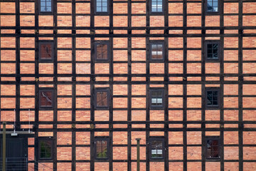 
a row of vertical and horizontal windows in a red brick and timber frame wall