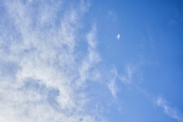 A tranquil sky with scattered wispy clouds and sunlight