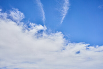 A serene blue sky dotted with wispy white clouds, conveying a sense of tranquility and spaciousness.