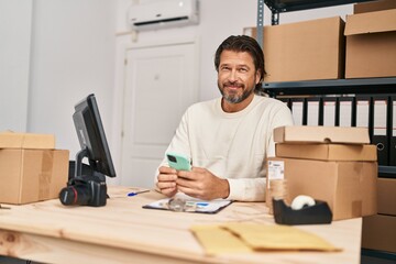Middle age man ecommerce business worker using smartphone at office