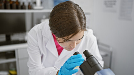 Determined young hispanic woman scientist, with beautiful hairstyle, engrossed in serious research...