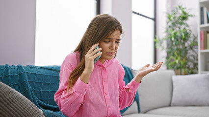 Unhappy, worried young beautiful hispanic woman talking with serious problems via smartphone,...