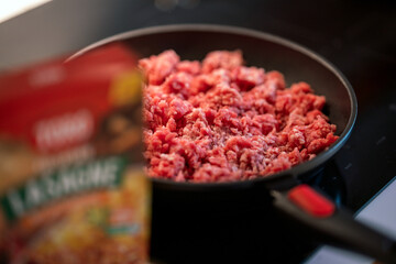 mince meat in frying pan next to lasagna packaging.