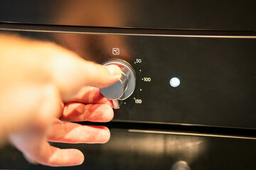 Hand setting the right temperature on oven.