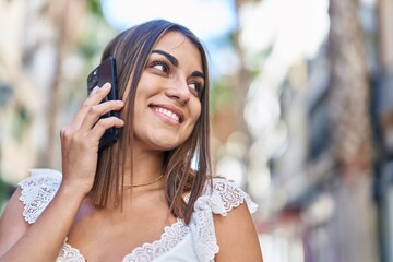 Young beautiful hispanic woman smiling confident talking on the smartphone at street