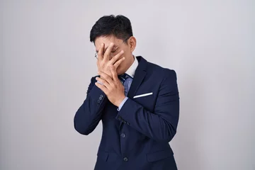 Fotobehang Young asian man wearing business suit and tie with sad expression covering face with hands while crying. depression concept. © Krakenimages.com