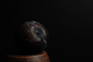 large plum with drops of water on a black background