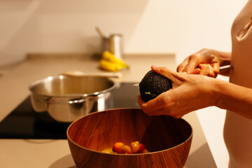 Woman's hands starting to cut an avocado for a salad bowl