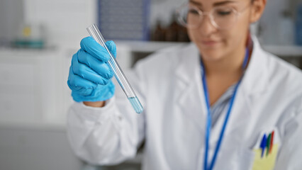 Brilliant young redhead woman scientist engrossed in medical research, meticulously measuring liquid in a test tube, security gloves on, at the busy heart of a bustling laboratory.