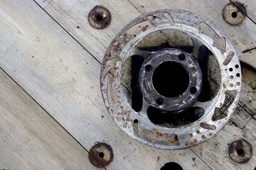 Close-up of old car brake disc lying on a wooden floor