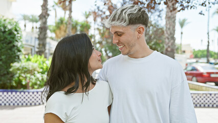 A smiling couple embracing outdoors in a lush park on a sunny day.