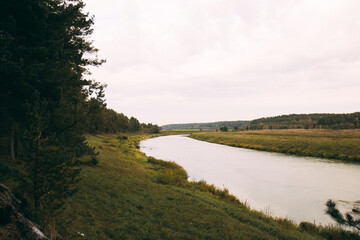 The landscape of the river with green banks. Autumn forest along the river. The river cuts through the fields. Beautiful river banks.