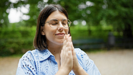 Young beautiful hispanic woman praying with closed eyes at the park in Vienna