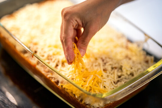 adding cheese on top of lasagna