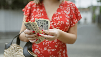 Young woman caught up in the tokyo city hustle, hands busy counting stacks of yen banknotes amidst...