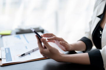 Close-up of a businesswoman professional's hands using a smartphone, interacting with digital data, in a corporate office setting.