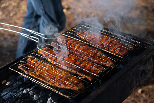 Smoky flavor infuses mackerel fillets as they char-grill on a wire rack, in the tranquil Beit Shemen forest near Jerusalem, under the golden light of sunset