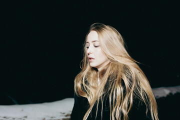 young blond woman with blue eyes dancing in the dark night of an very cold snow winter