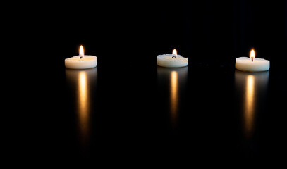 trois petites bougies blanches chauffe plat et leur reflet sur une table noire avec de l'espace vide