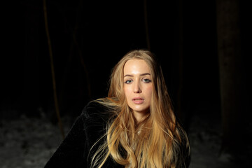 young blond woman with blue eyes dancing in the dark night of an very cold snow winter