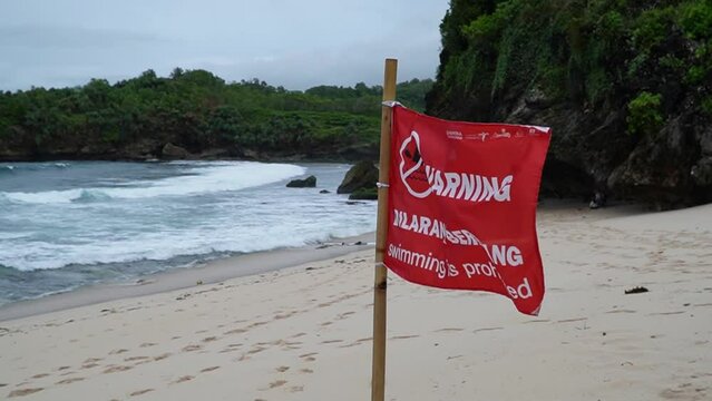 Red warning flag indicates that swimming is not allowed on the beach because of the dangerous contours of the beach and large waves. No swimming sign is in the form of a red flag with a description