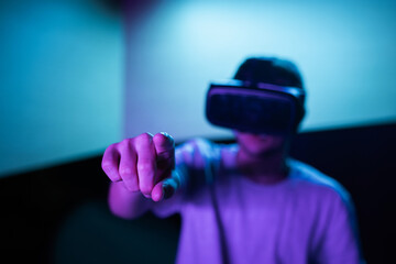 Young man interacting in a digital world, using virtual reality headset with motion tracking tech, making hand gestures in the air.