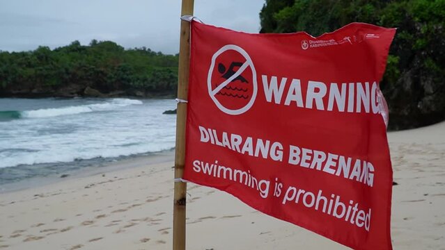 Red warning flag indicates that swimming is not allowed on the beach because of the dangerous contours of the beach and large waves. No swimming sign is in the form of a red flag with a description