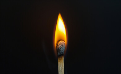 Burning wooden match on black background.