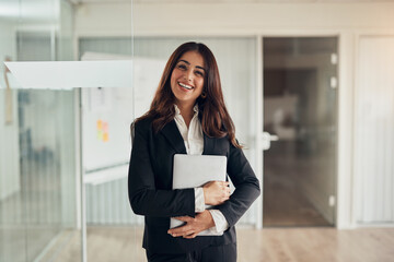 Smiling businesswoman standing at the entrance to an office boardroom