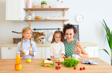 Happy young brunette mother with cute little kids having breakfast