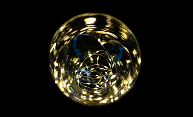 vase transparent avec une guirlande lumineuse à l'intérieur devant un fond noir vu d'en haut - texture abstraite