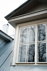 Beautiful window frames of the old building in which the trees are reflected, cloudy