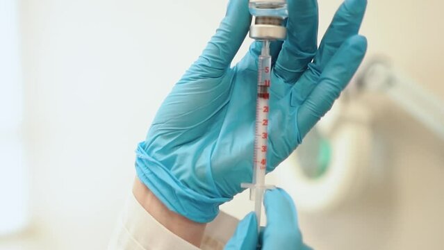 a doctor in a medical hospital is preparing to give an injection with a vaccine to a patient against a virus, close-up, vaccination