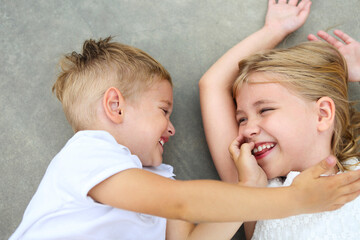 Portrait of adorable brother and sister smile and laugh together outdoors