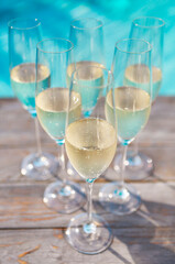 Champagne glasses on wooden background near pool
