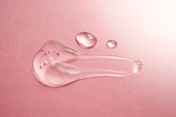 A drop of transparent cosmetic gel on a pink background.