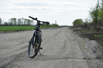 Obraz premium Mountain bike. stands on a field road. spring or autumn. concept of cycling, repair or breakage, sports, outdoor activities. bike on trail, front wheel in focus. healthy lifestyle