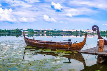Old wooden boat on lake. Wood empty rowboat moored near shore. Summer landscape with mooring...