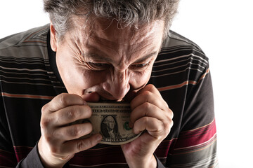 A middle-aged man with gray hair in casual clothes bites a stack of $1 bills