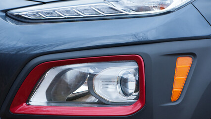 headlight of modern prestigious car closeup. beautiful headlights of a car. dark gray color, red...