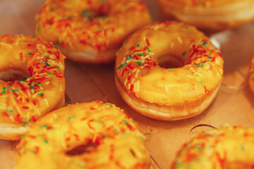 Many donuts with yellow icing on the counter in a store. Traditional mouth-watering sweets. Close-up.