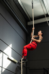 Strong woman climbing rope in a cross training gym