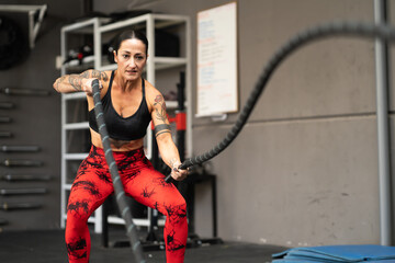 Fototapeta na wymiar Strong mature woman working out with battle ropes
