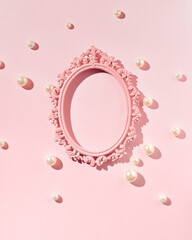 Oval vintage picture frame, empty, pearl beads scattered on pastel pink background, creative copy space, place for presentation, text, greetings, feminine, elegant minimalist style.