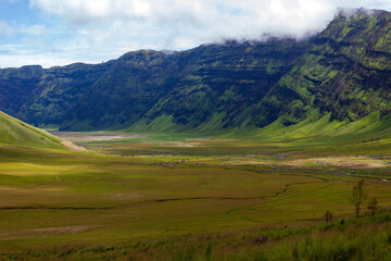 Landscape of green hills in the mountains on a cloudy day. Location of Mount Bromo in Bromo Tengger Semeru National Park, East Java, Indonesia