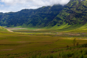 Obraz premium Landscape of green hills in the mountains on a cloudy day. Location of Mount Bromo in Bromo Tengger Semeru National Park, East Java, Indonesia