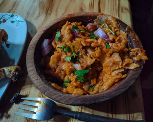 A traditional Algerian dish called “chakhchoukha bou saada” served in a wooden plate, with...