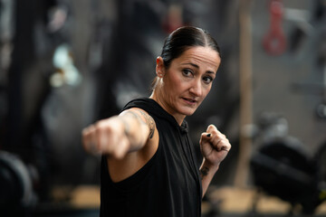 Female boxer throwing a jab while shadowboxing in the gym - obrazy, fototapety, plakaty