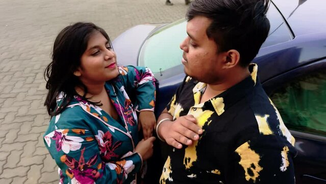 young couple talking outdoor having conversation luxury car in background