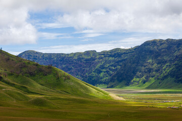 Obraz premium Landscape of green hills in the mountains on a cloudy day. Location of Mount Bromo in Bromo Tengger Semeru National Park, East Java, Indonesia